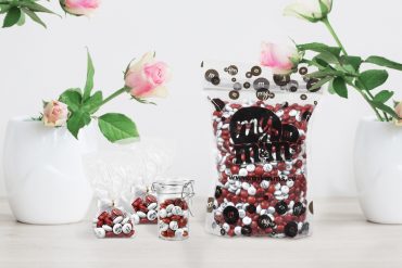 Tüte mit personalisierten M&Ms und Vasen mit Rosen