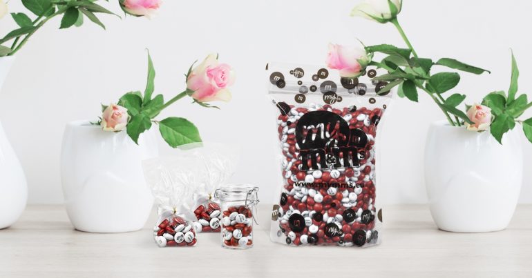Tüte mit personalisierten M&Ms und Vasen mit Rosen