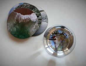 Blick von oben auf Untersetzer mit Fotos und Wasserglas