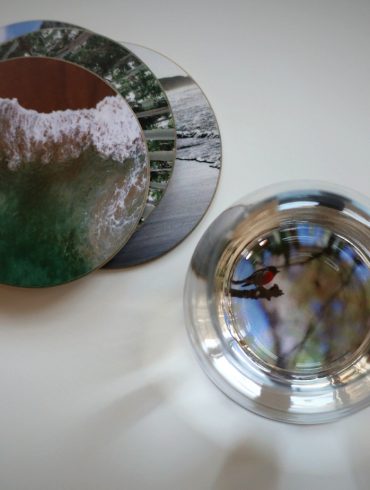 Blick von oben auf Untersetzer mit Fotos und Wasserglas