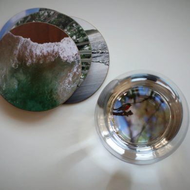 Blick von oben auf Untersetzer mit Fotos und Wasserglas